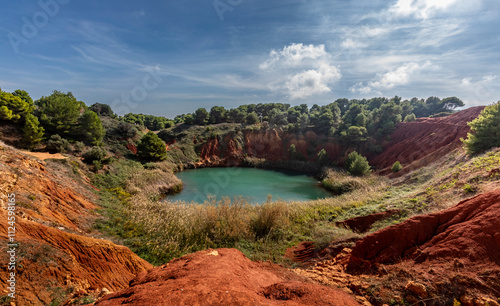 Scenic view of Bauxite Lake near Otranto in Apulia, Italy with red earth and lush vegetation photo