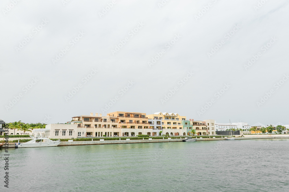 Punta Cana Architecture with port and Private Yacht. Dominican Republic. Luxurious Waterfront Residences With Yacht Docked Alongside Lush Palm Trees Punta Cana Architecture with port and Private Yacht. Dominican Republic. Luxurious Waterfront Residences With Yacht Docked Alongside Lush Palm Trees