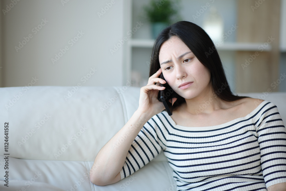 Worried asian woman talking on phone sitting at home Worried asian woman talking on phone sitting at home