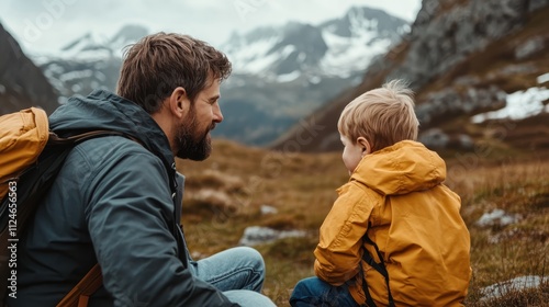 A father and son share a bonding moment in the wilderness, sitting together with backpacks in a serene mountain valley setting, highlighting the theme of family adventure. photo