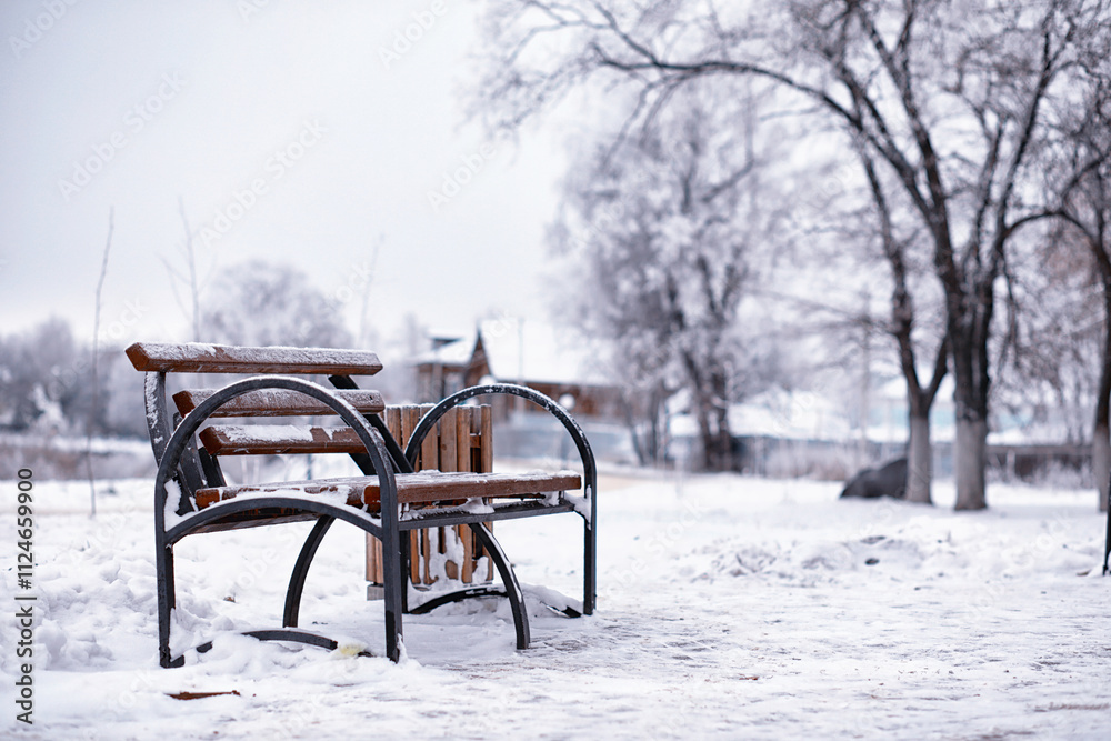 park bench on a winter alley at snowfall. bench with snow after snowstorm or in snow calamity in europe park bench on a winter alley at snowfall. bench with snow after snowstorm or in snow calamity in europe