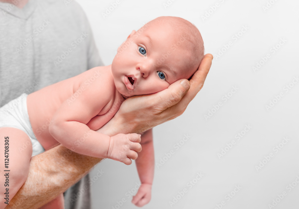 newborn baby lies on dad's arm and looks at camera newborn baby lies on dad's arm and looks at camera