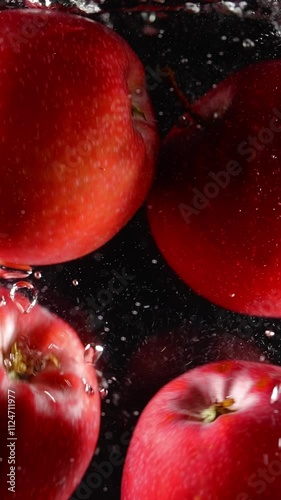 red apples falling in the water super slow motion vertical video. dark red and black color. fresh organic crops, fresh healthy food