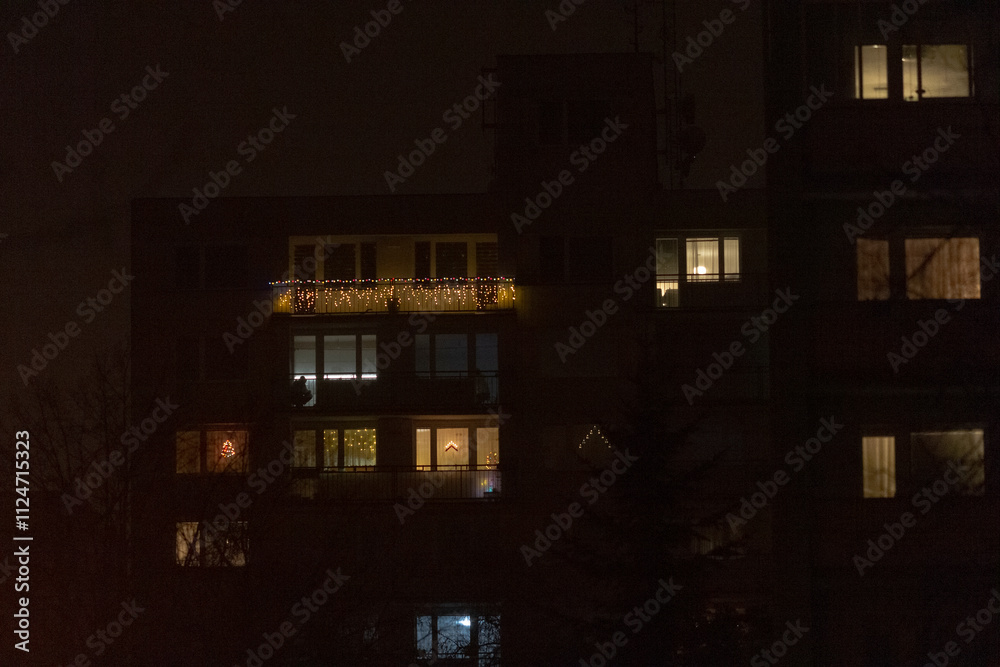 At night, a building with numerous windows is beautifully illuminated, providing a striking contrast against the surrounding darkness