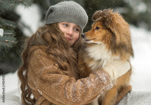 girl's looking at her collie  dog and smiling outside in the winter