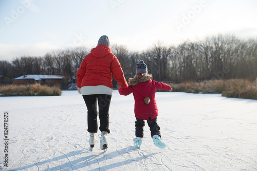 grandmother and little granddaughter skate on a frozen lake. grandmother teaches granddaughter to skate