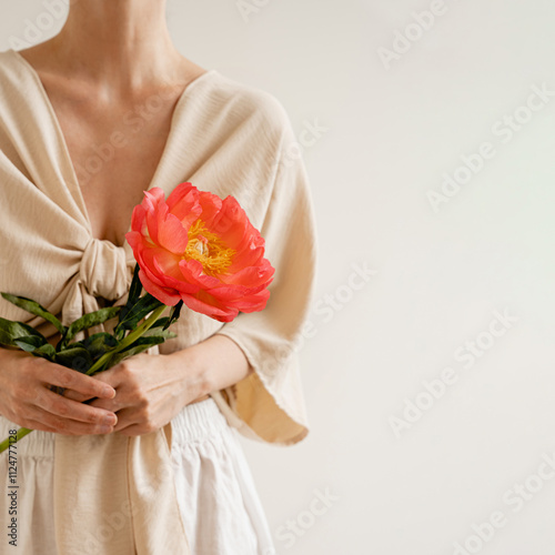 Modern Serenity. Woman Holding Bright Bloom, Minimalist Fashion, Neutral Palette, Artistic Expression, Contemporary Aesthetic, Floral Elegance
