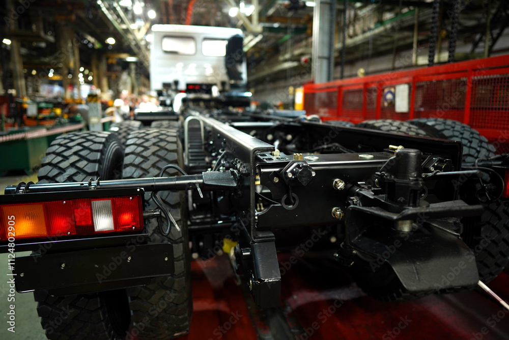 Fototapeta premium Truck production line. Assembly line. Engine install on frame of Wheel chassis of Heavy duty truck plant. Workshop production of Heavy duty trucks. Trucks Manufacture. Assembly line of truck factory.