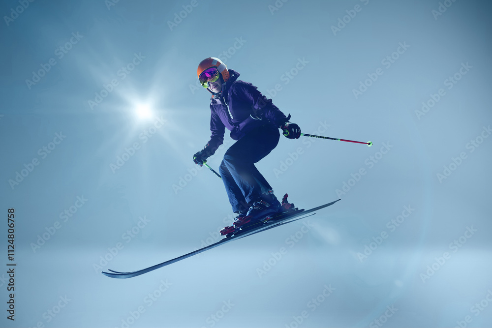 Obraz premium Skier leans into precise descent, her poles and skis aligned for ultimate control against blue background with sunbeam. Concept of extreme sport, Christmas holidays. Ad