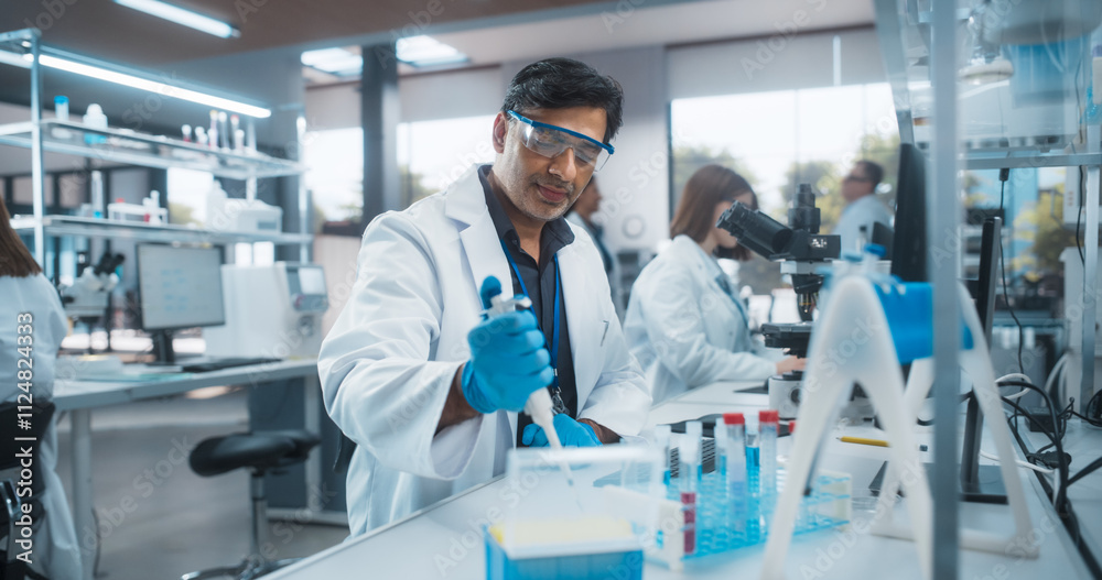 Indian Male Research Scientist Using Micropipette to Mix Liquids in a Test Tube in a Modern Laboratory. Scientists are Conducting Research with the Help of Microscopes and Desktop Computers Indian Male Research Scientist Using Micropipette to Mix Liquids in a Test Tube in a Modern Laboratory. Scientists are Conducting Research with the Help of Microscopes and Desktop Computers