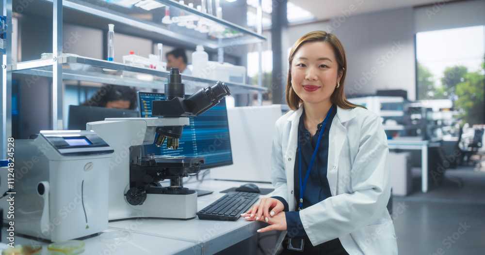 Portrait of a Japanese Female Scientist Posing for Camera, Smiling. Young Asian Biologist in a White Coat Working in a Modern Laboratory, Researching Medical Drug Products and Genome Editing