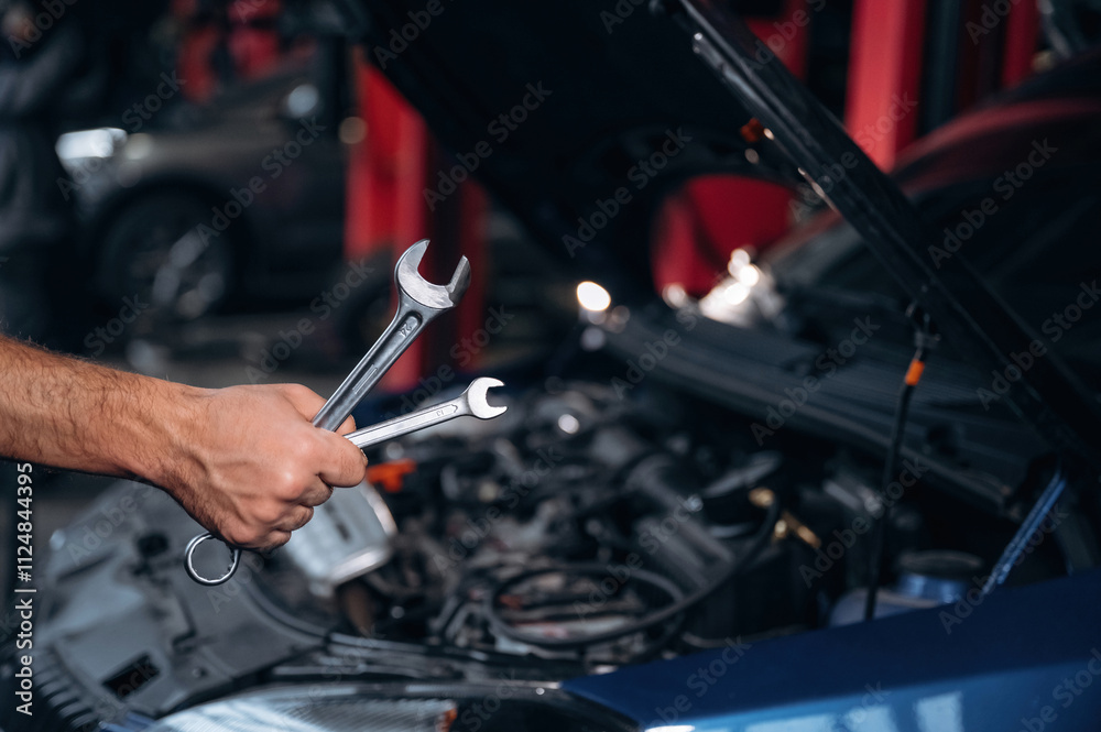 Blue automobile, working. Close up view of mechanic in car service station Blue automobile, working. Close up view of mechanic in car service station