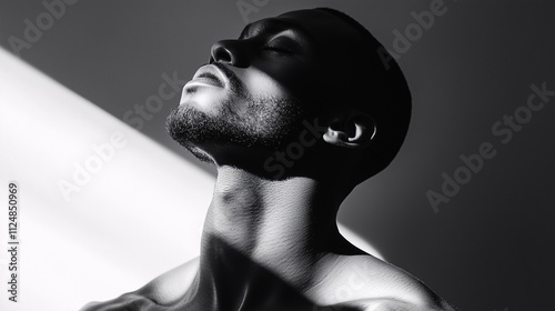 Black and white portrait of a man with dramatic shadows, showcasing masculinity and introspection
