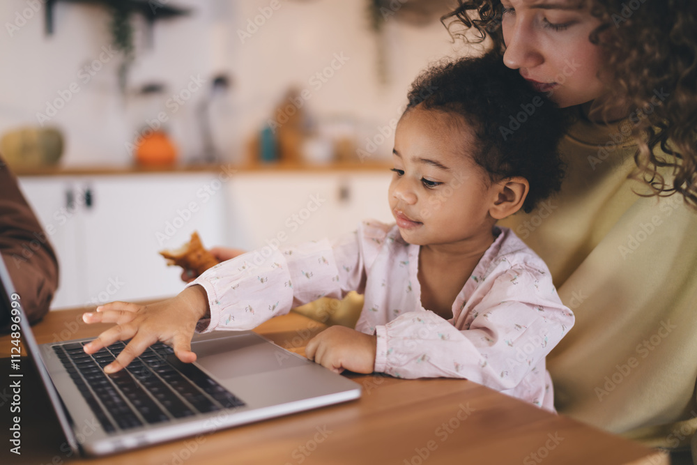 Working mother balancing professional life and parenting in home interior. Mixed-race child enjoys time with mother during casual business meeting via modern laptop computer connected to 4g Working mother balancing professional life and parenting in home interior. Mixed-race child enjoys time with mother during casual business meeting via modern laptop computer connected to 4g