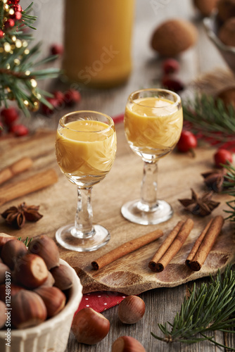 Two shot glasses of Eiercognac with spices, hazelnuts and Christmas decoration photo