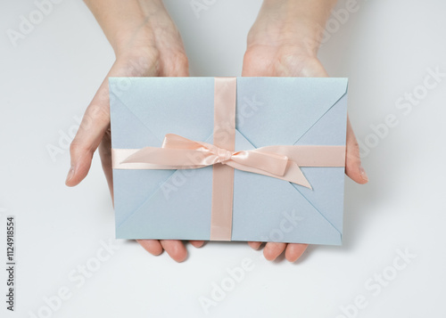 Hands holding blue gift envelope.