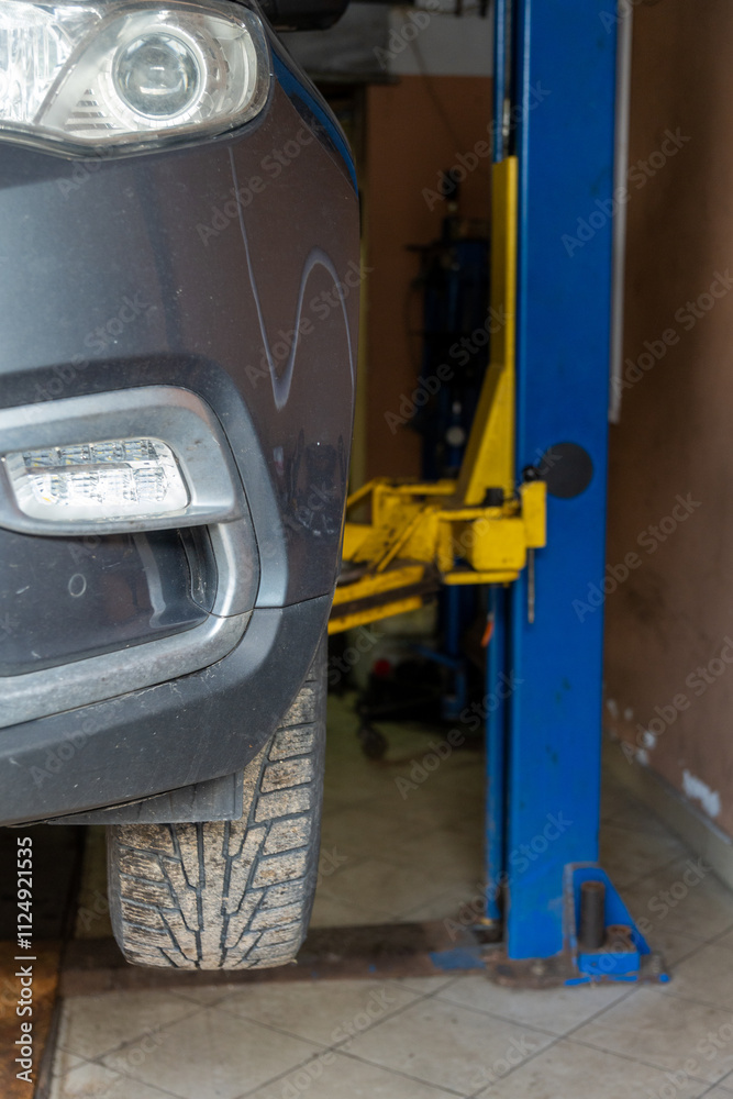 Gray car on auto lift in garage for repair and maintenance service. Gray car on auto lift in garage for repair and maintenance service.