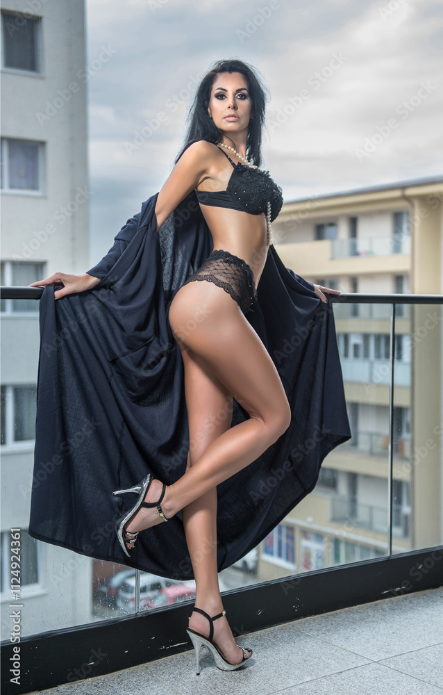 Beautiful brunette woman in black lingerie posing in the city. Elegant and sensual brunette girl with long hair in black lingerie posing on the roof.