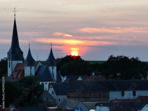 Drohnenansicht von Herrnsheim – Kirche und Häuser bei Sonnenuntergang in stimmungsvoller Atmosphäre photo