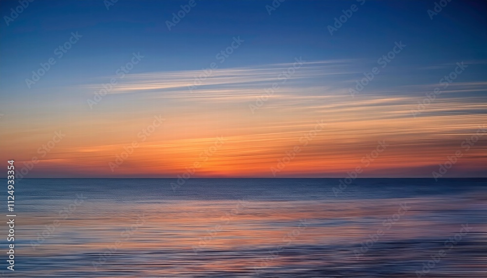 Fototapeta premium Seascape Serenity: A tranquil sunset paints the sky with hues of orange and blue, reflecting on the calm, rippling waters of the ocean. The soft.
