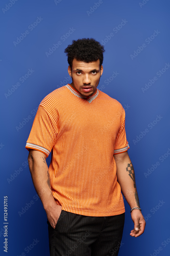 A handsome young man stands with a serious expression, showcasing his stylish orange shirt. A handsome young man stands with a serious expression, showcasing his stylish orange shirt.