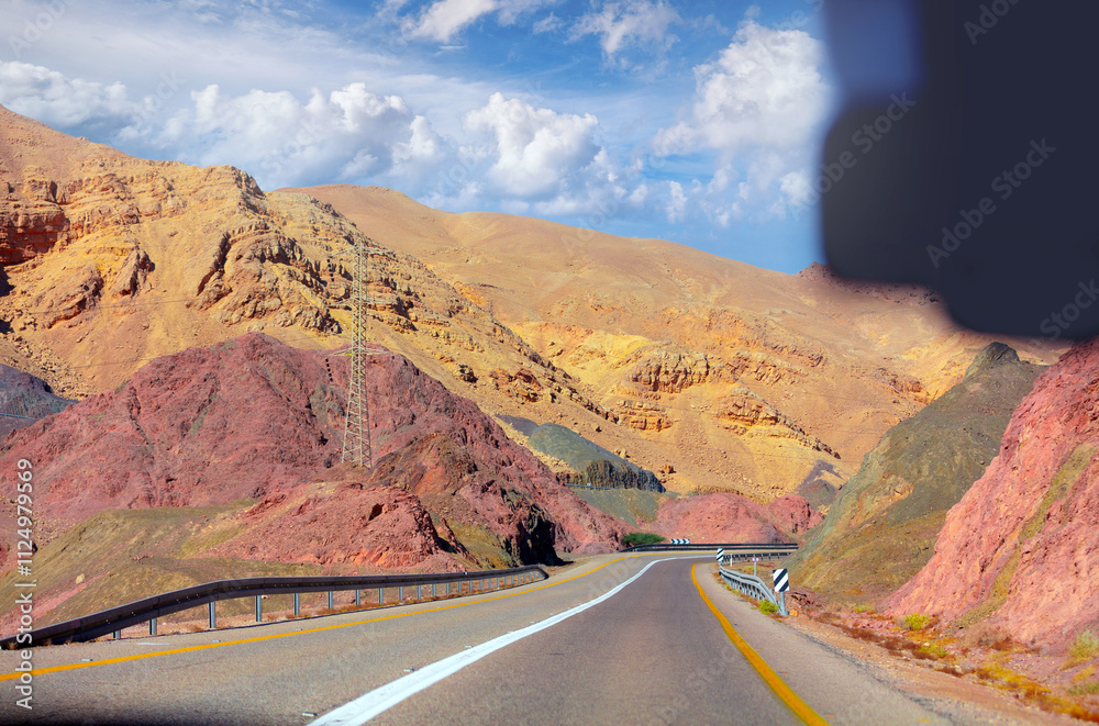 Highway in the mountain desert. Sandstone mountains along the road. View from car