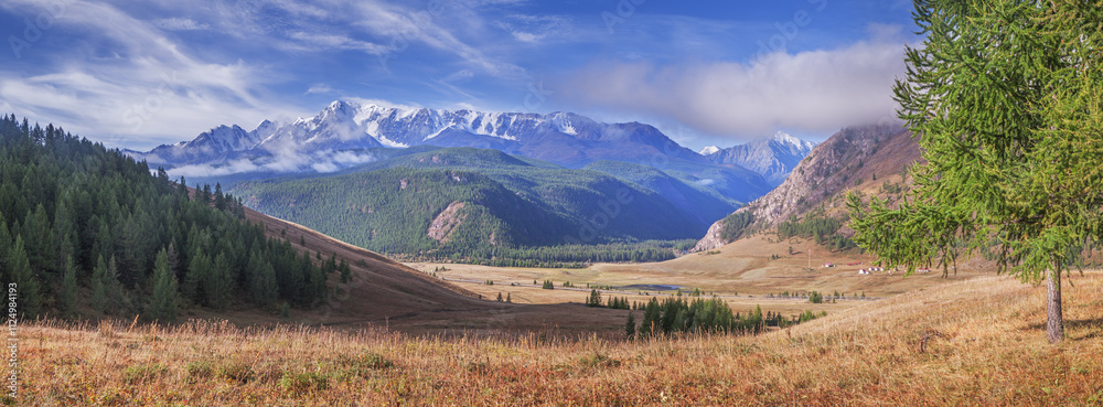 Fototapeta premium Mountain valley in the morning light, snow-capped mountain peaks in clouds, summer travel, panoramic view 