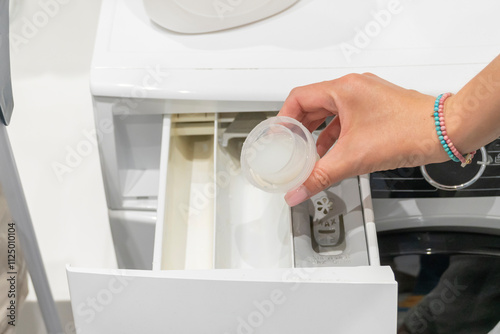 Close-up photo of woman adding cleaning solution to washing machine	