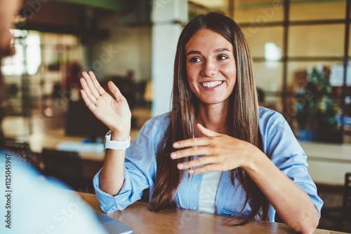 Happy successful hipster girl explaining information to male friend sitting in front, positive man and woman talking and discussing ideas for new startup project at spending time in coworking space photo