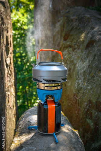 Camping kettle on a tourist gas stove against the backdrop of cliff photo