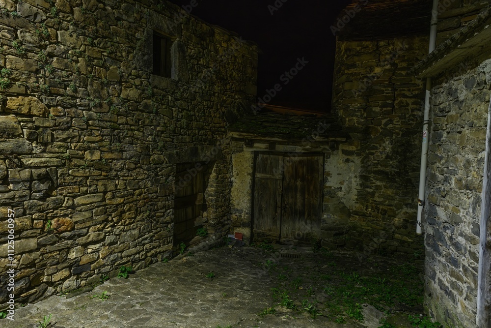 Charming stone alley at night with bright lights in Torla - Huesca Charming stone alley at night with bright lights in Torla - Huesca