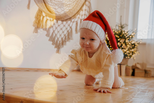 Child in a red Christmas hat crawls under the Christmas tree