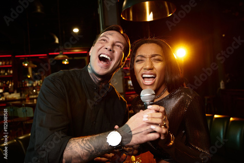 Lively multicultural couple shares a joyful moment on their date while singing at a bar. photo