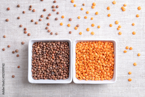 Dried red and brown lentils in square shaped white bowls on linen. Shelled and unshelled mountain lentils with brown seed coats and orange-red seeds. Also known as Nipper, Masoor dal, Red Chief, etc.