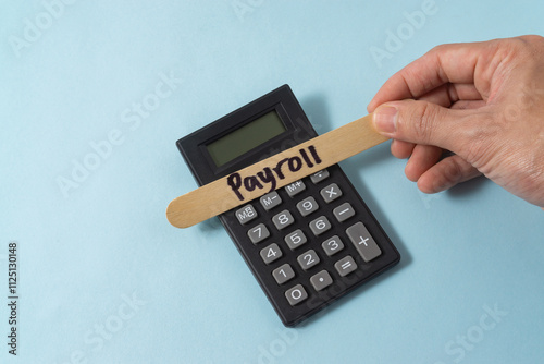 Financial concept with a hand writing payroll on ice cream stick