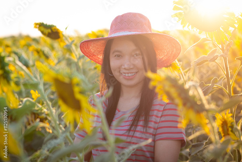 Portrait of beautiful asian girl in sunflower field at sunset. Beautiful asian woman in sunflower field at summer day.