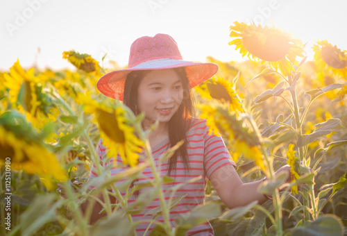 Portrait of beautiful asian girl in sunflower field at sunset. Beautiful asian woman in sunflower field at summer day.