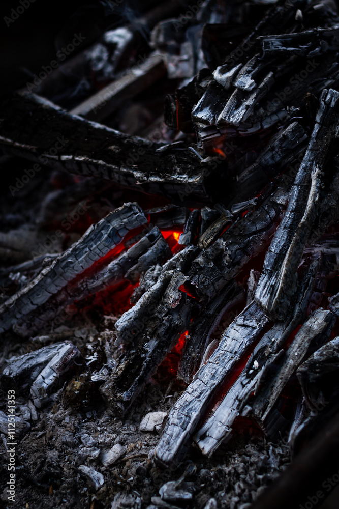 Orange fire and heat from burning firewood, glowing and burning, from charcoal, close-up at night with a dark background. Coziness from the fireplace atmosphere. Orange fire and heat from burning firewood, glowing and burning, from charcoal, close-up at night with a dark background. Coziness from the fireplace atmosphere.