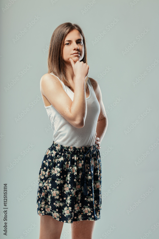 Fototapeta premium Young woman thinking and touching chin with hand