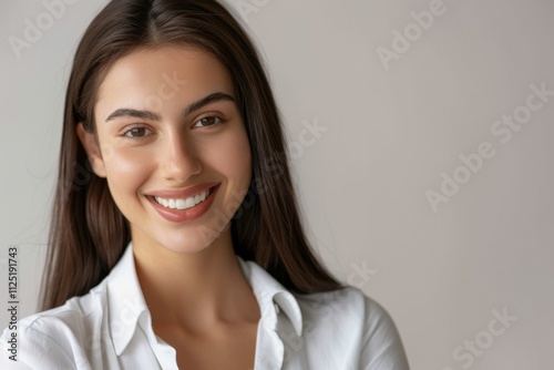 A beautiful millennial female leader radiates confidence while posing for a professional headshot. Her smile and demeanor reflect success and positivity in the workplace.