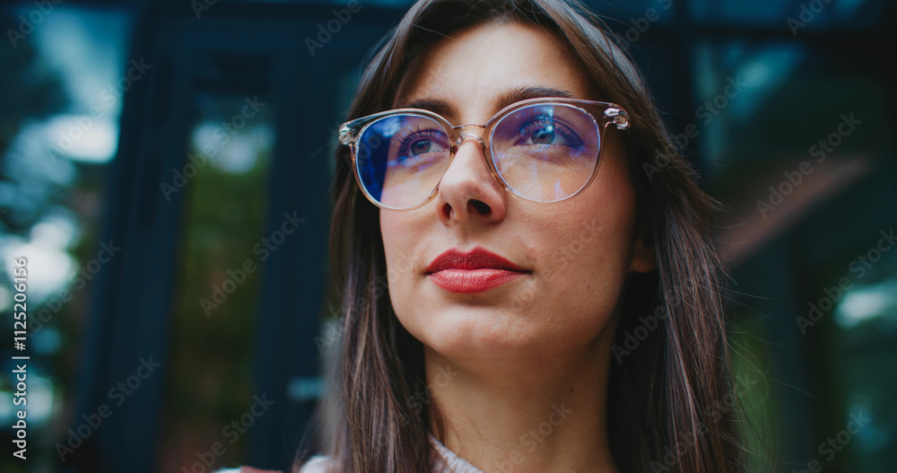 Attractive Caucasian woman looking at sky before glancing at camera and smiling. Wearing big round glasses for better vision. Portrait concept. Manager spending time outside during lunch break. Attractive Caucasian woman looking at sky before glancing at camera and smiling. Wearing big round glasses for better vision. Portrait concept. Manager spending time outside during lunch break.