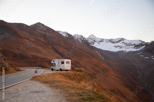 caravan in autumn orange mountain landscape on the pass surrounded with snowy a mountain peak