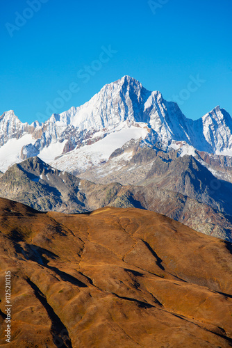 high mountain snowy peaks in the background of orange hills