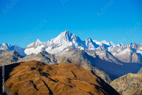 high mountain snowy peaks in the background of orange hills photo