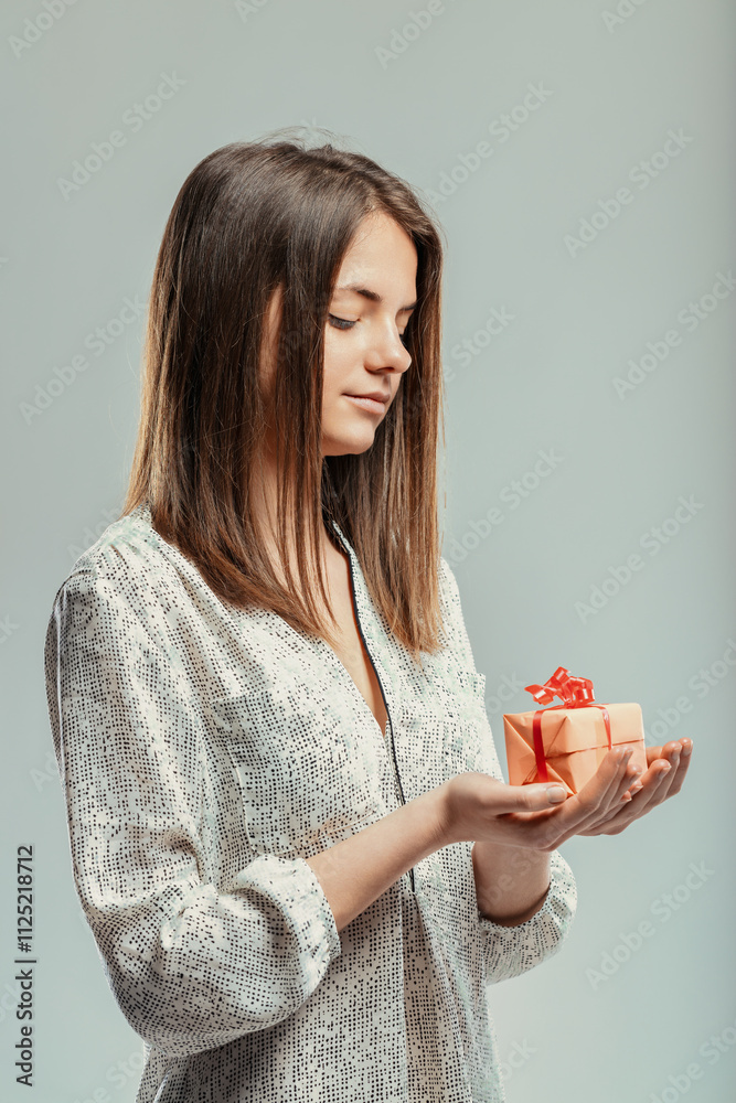 Young woman holding a small gift expressing gratitude and happin Young woman holding a small gift expressing gratitude and happin