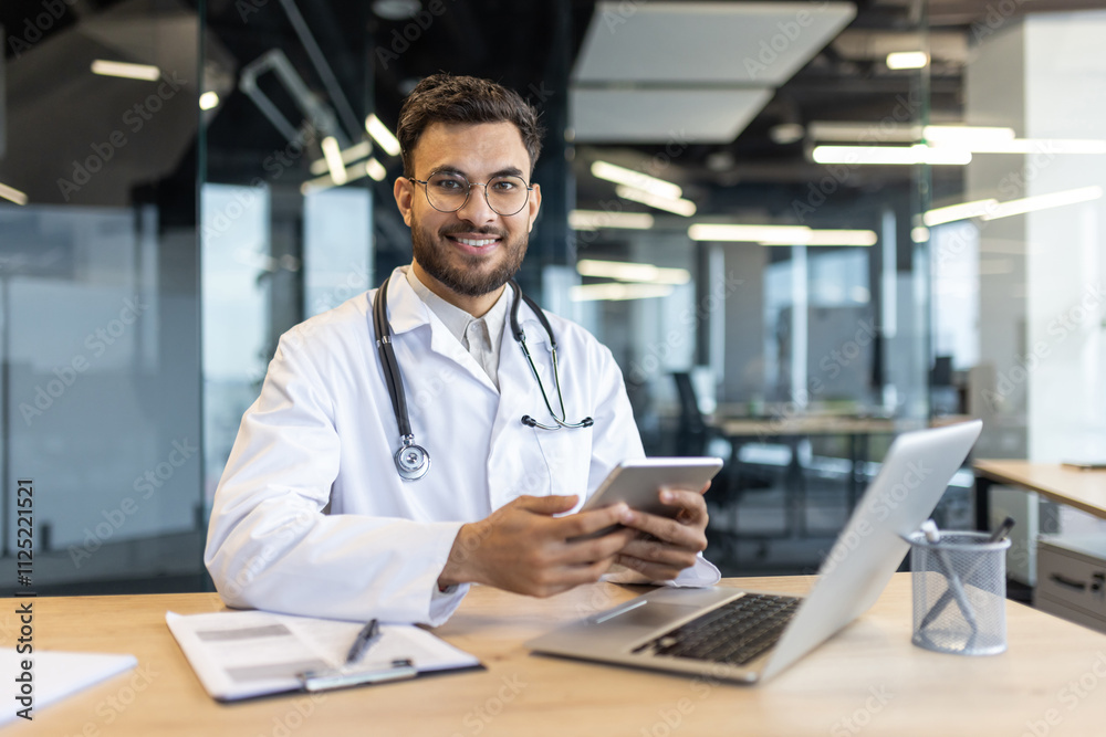 A doctor smiles as he uses a tablet and laptop in a modern office setting. The professional atmosphere and use of technology highlight efficiency and connectivity in healthcare environments. A doctor smiles as he uses a tablet and laptop in a modern office setting. The professional atmosphere and use of technology highlight efficiency and connectivity in healthcare environments.