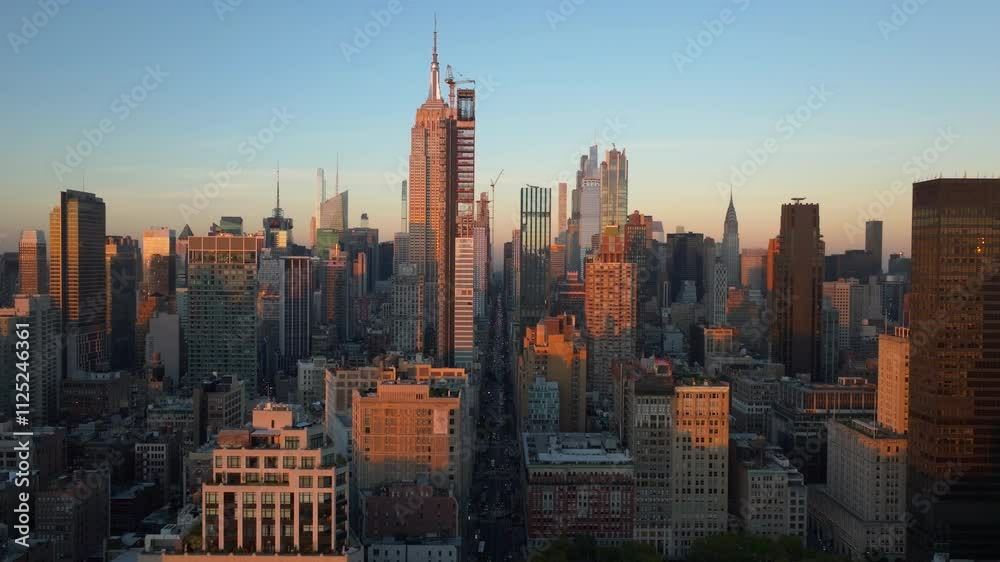 Aerial view of sun setting over Midtown Manhattan and the Empire State Building in New York City. Construction workers on a modern architecture skyscraper