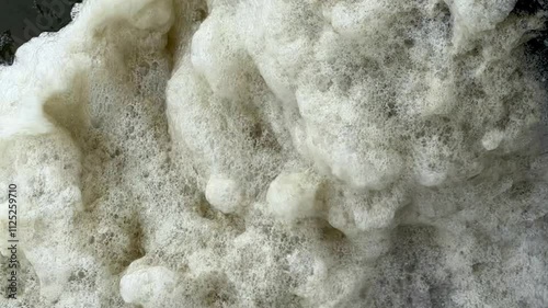 Slow motion of a pile of sea foam jiggling in the wind seen from above on Oak Island, North Carolina
