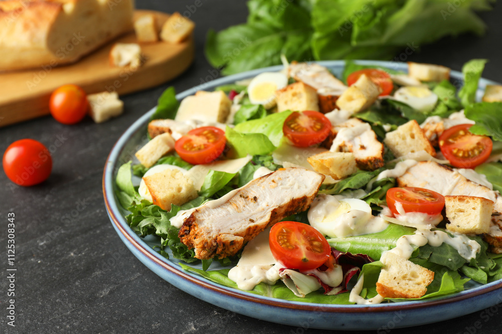 Tasty Caesar salad with chicken and tomatoes on dark gray textured table, closeup Tasty Caesar salad with chicken and tomatoes on dark gray textured table, closeup