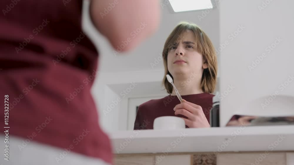 Young man looking to his reflection in the bathroom, getting ready to his morning routine Young man looking to his reflection in the bathroom, getting ready to his morning routine